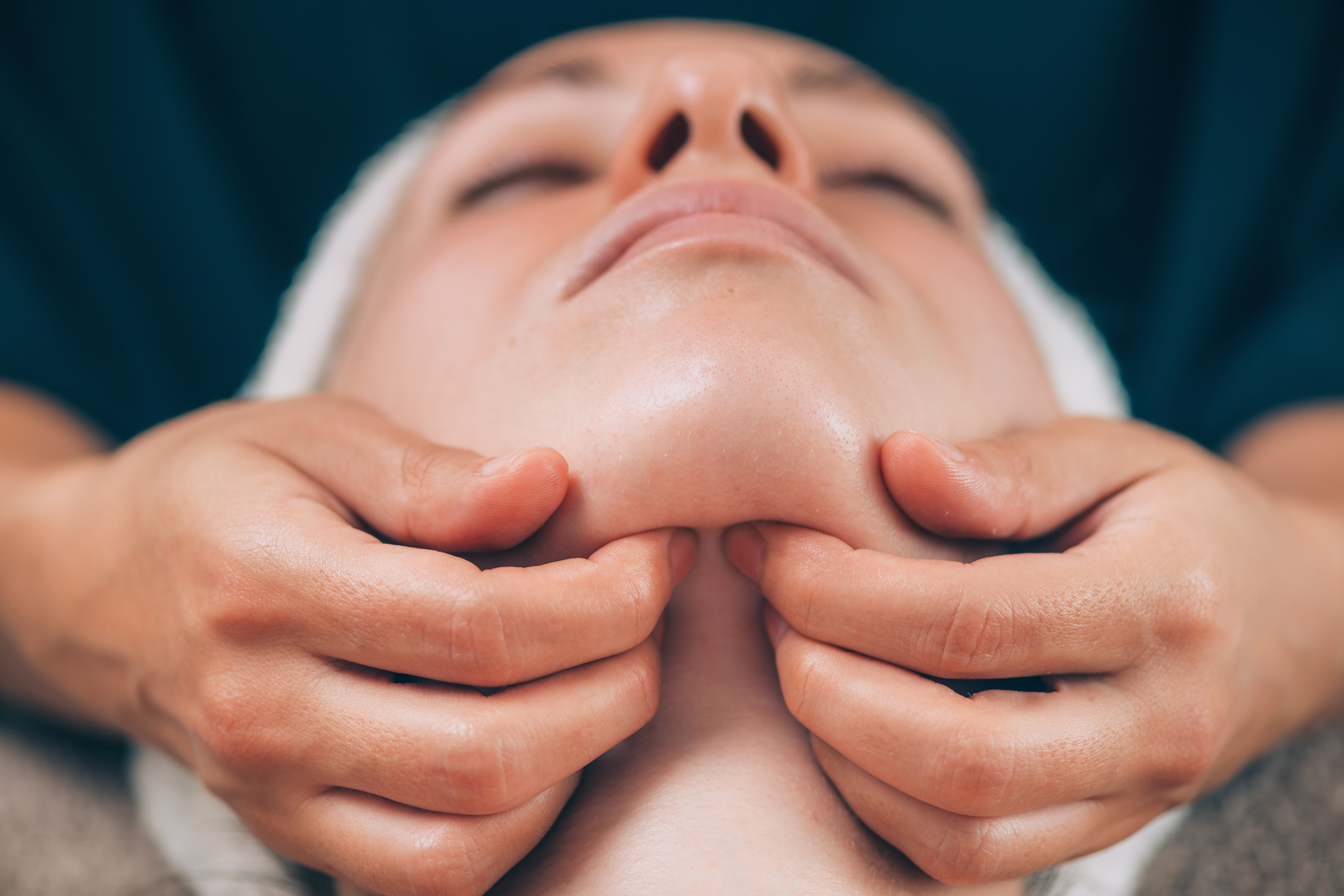 Close-up of a young woman receiving chin and jawline face lifting massage