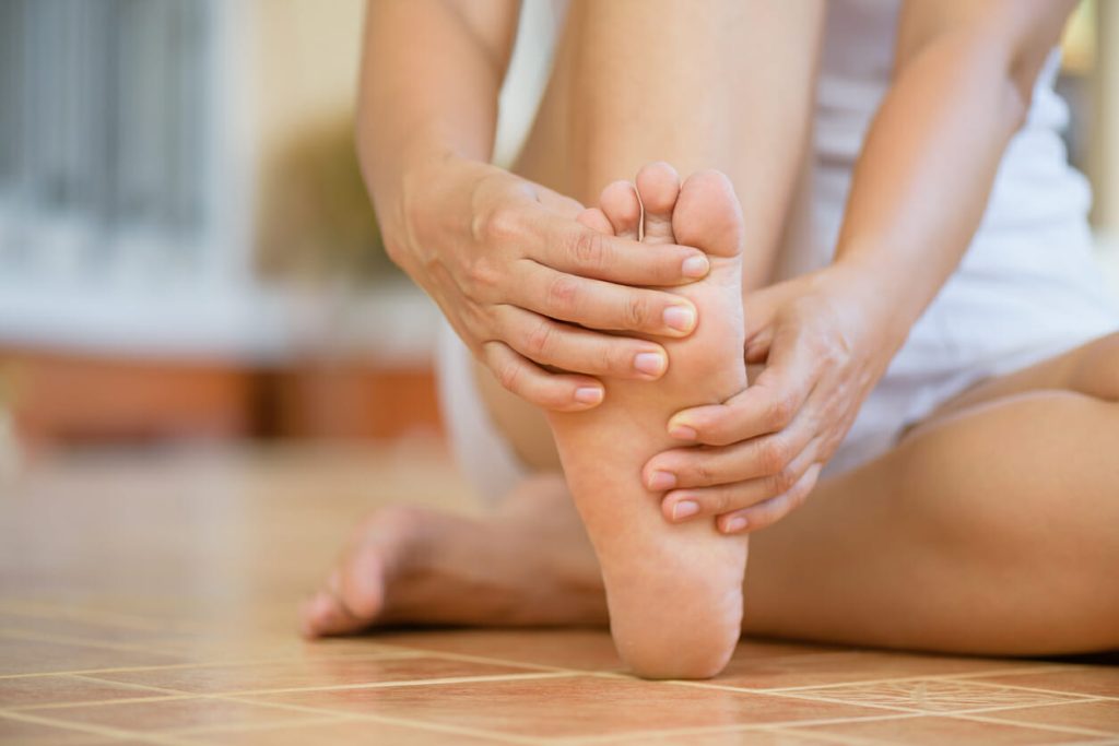 Closeup young woman feeling pain in her foot at home.