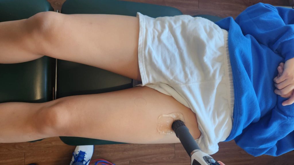 shockwave gun on the front of a patients hip and leg