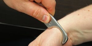 a metal tool being applied to a patients thumb for treatment