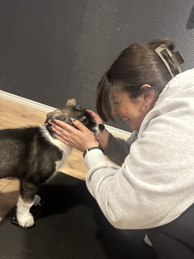 A photo of psychotherapist Alessia Zita at puppy yoga. In the photo she is smiling while holding a brown husky puppy