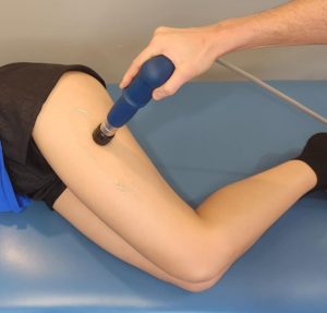 shockwave applicator on the side of a patients leg