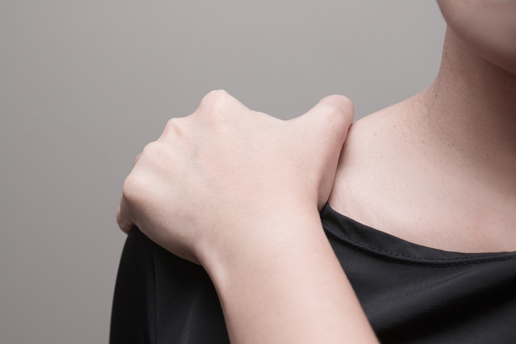 Young woman suffering from pain in shoulder.