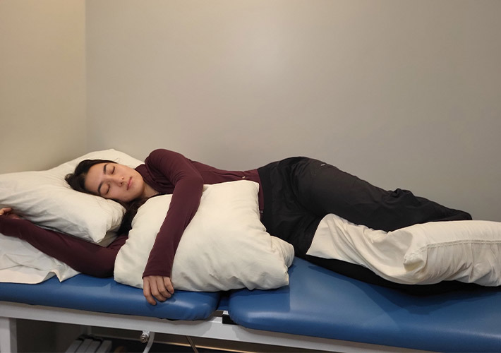 A team member from Oakville Clinic showing best sleeping position on side