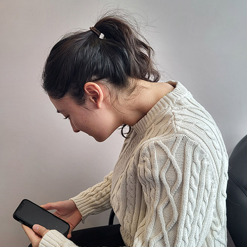 A female looking at her phone with text neck